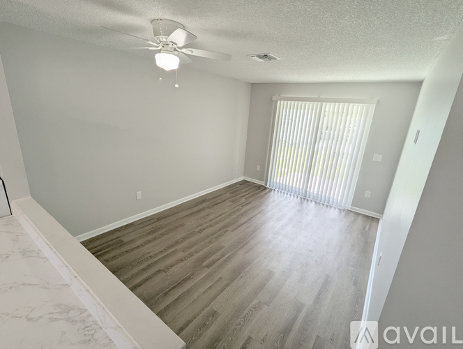 A spacious room with a ceiling fan and wooden flooring.