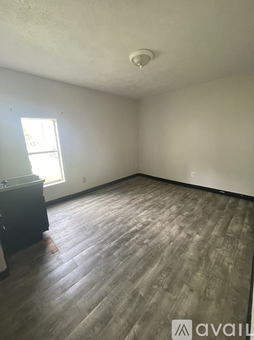 A room with wooden flooring and a window letting in light.