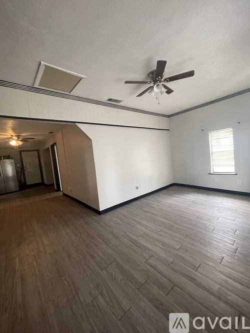A room with a ceiling fan and wooden flooring.