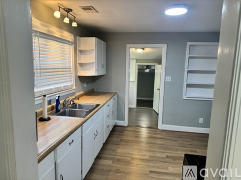 A kitchen with white cabinets and a wooden countertop.