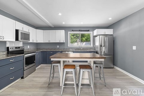 A kitchen with a table and bar stools in the middle.