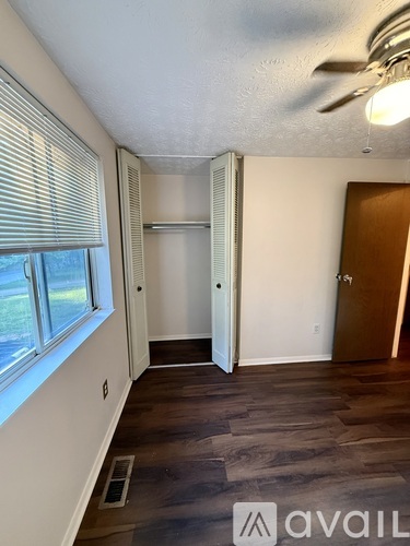 A room with a ceiling fan and a window with blinds.