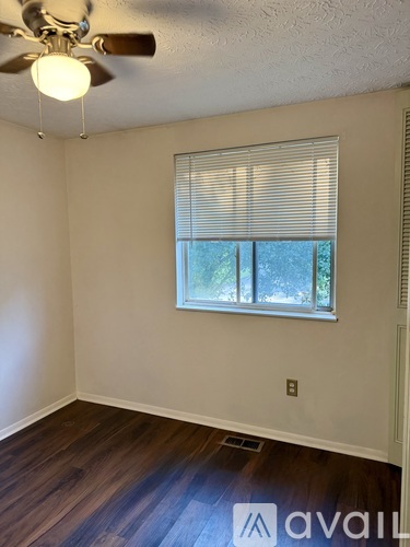 A room with a ceiling fan and a window with blinds.