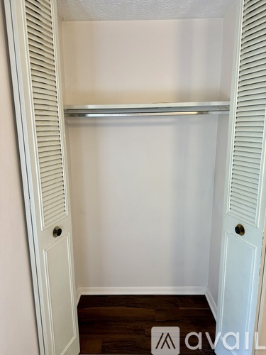 A white closet with a shelf and a wooden floor.