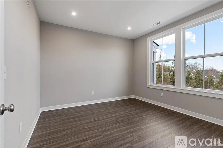 A room with a door, window, and wooden flooring.