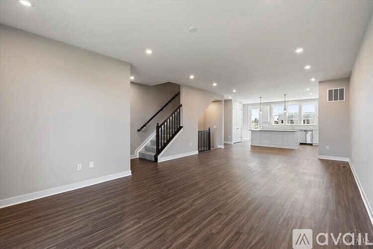A spacious living room with wood flooring and a staircase leading to the upper level.