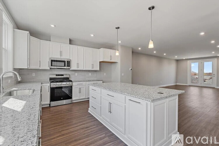 A spacious kitchen with white cabinets and a granite countertop.