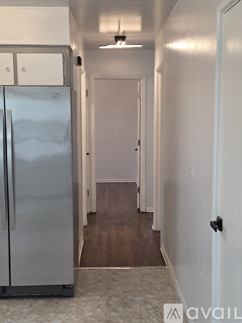 A kitchen with a refrigerator and a door on the right.