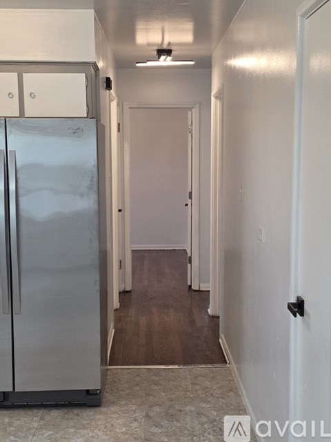 A kitchen with a refrigerator and a door on the right.