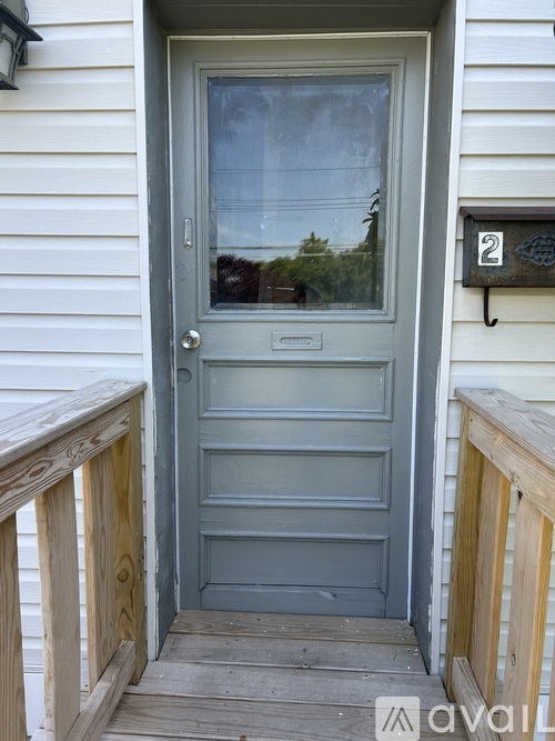 A grey door with a glass window and a mailbox on the wall.
