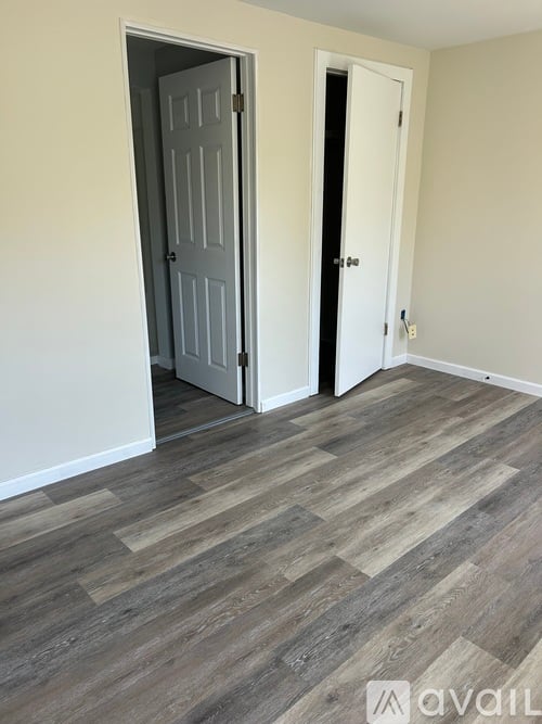 A room with a grey door and a wooden floor.