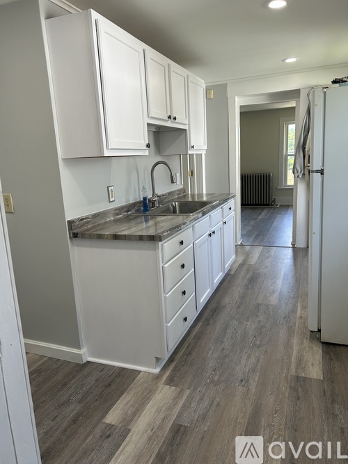 A kitchen with white cabinets and a wooden floor.