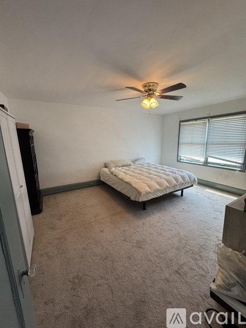 A bedroom with a bed, a ceiling fan, and a window with blinds.