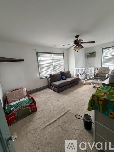 A living room with a couch, a fan, and a window with blinds.