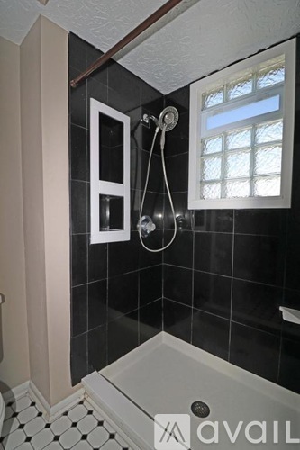 A bathroom with black tiles and a white shower tub.