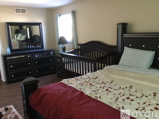 A bedroom with a bed, dresser, and mirror.
