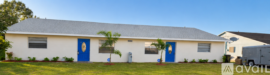 A white house with blue doors and windows is for sale.
