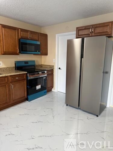 A kitchen with a refrigerator, microwave, and oven.