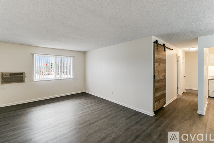 A room with wooden floors and a window with blinds.