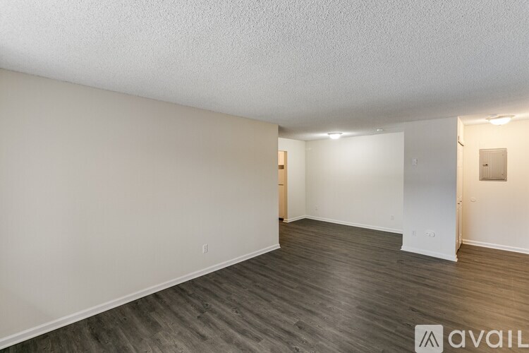 A spacious room with wooden flooring and white walls.