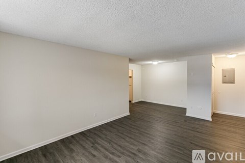 A spacious room with wooden flooring and white walls.