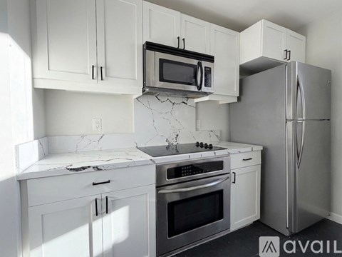 A kitchen with white cabinets and a marble countertop.