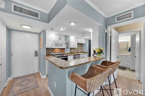 A kitchen with a marble countertop and a bar stool.