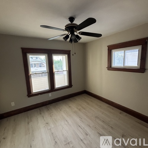A room with a ceiling fan and two windows.