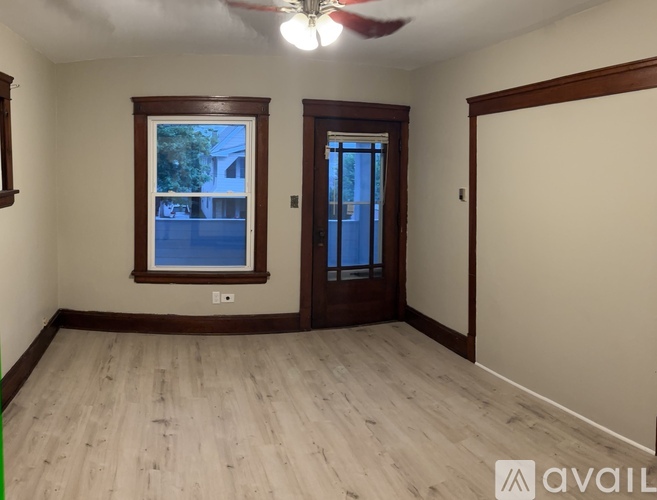 A room with a ceiling fan and a window with a view of a tree and a building outside.