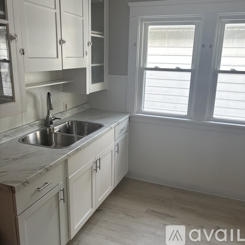 A kitchen with white cabinets and a marble countertop.