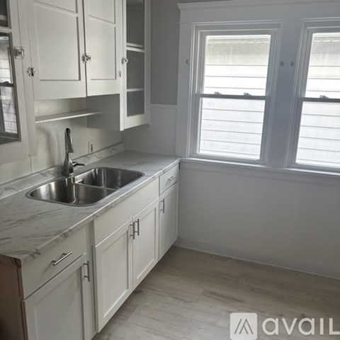 A kitchen with white cabinets and a marble countertop.