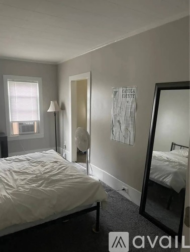 A bedroom with a bed, a mirror, and a lamp.
