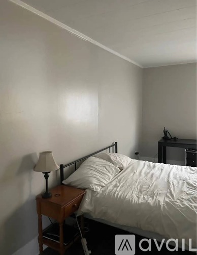 A bedroom with a bed, nightstand, and lamp.