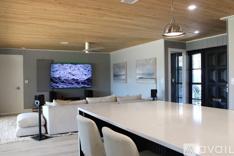 A modern living room with a large white table and a television mounted on the wall.