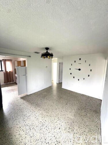 A white room with a ceiling fan and a clock on the wall.