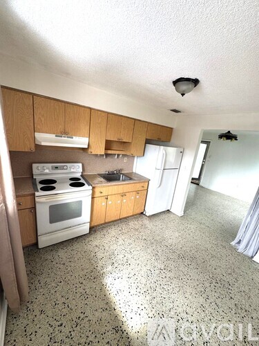 A kitchen with a white stove top oven and a white refrigerator.