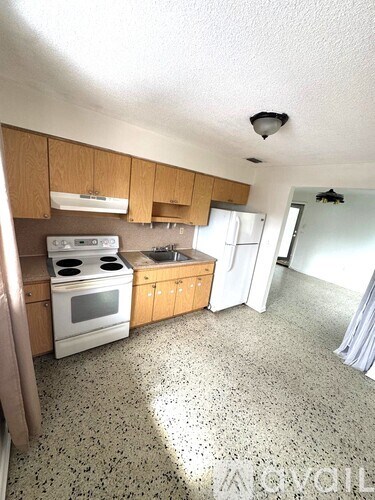 A kitchen with a white stove top oven and a white refrigerator.
