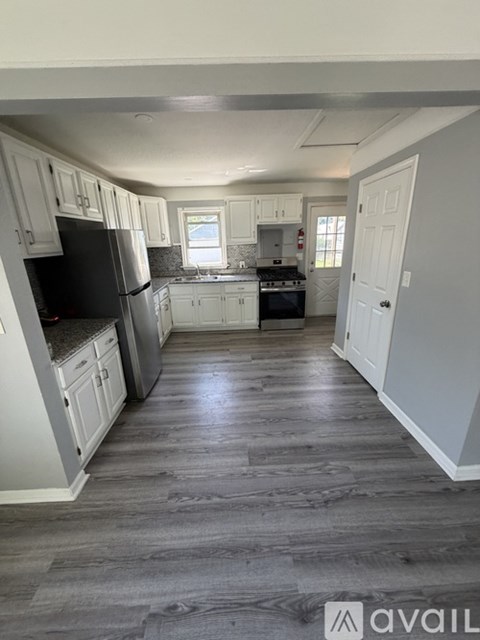 A kitchen with white cabinets and a black refrigerator.