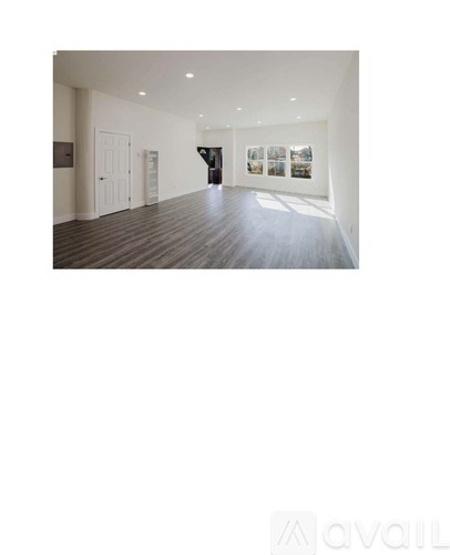 A spacious room with wooden floors and white walls.