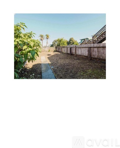 A narrow waterway runs through a dry, grassy area with a fence on one side and a row of trees on the other.