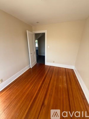 A room with wooden floors and a doorway leading to another room.