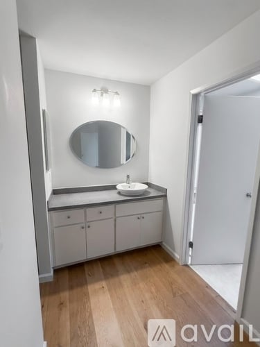 A bathroom with a sink, mirror, and cabinets.
