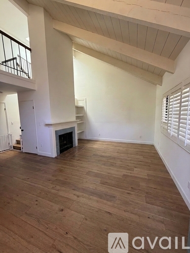 A spacious room with wooden flooring and a fireplace.