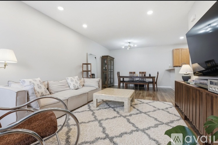 A living room with a white sofa, a wooden cabinet, and a TV.