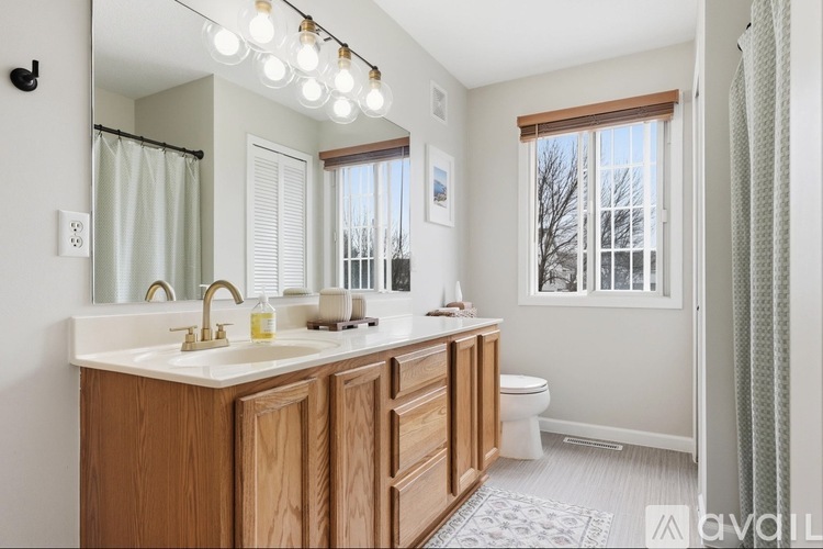 A bathroom with a wooden vanity and a window with a view of trees.