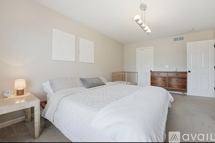 A bedroom with a large bed and a nightstand with a lamp.