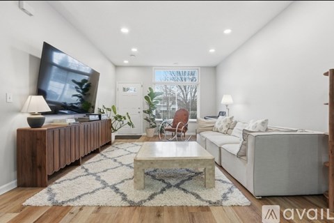 A living room with a white couch, a wooden cabinet, and a rug on the floor.