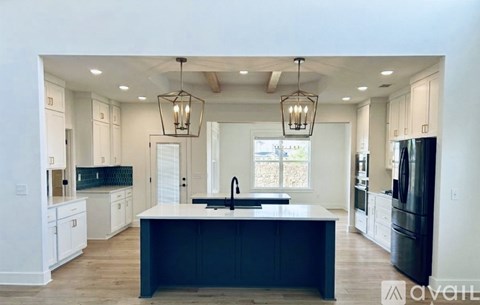 A modern kitchen with a large island and pendant lights.