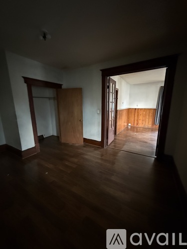 A room with wooden floors and a doorway leading to another room.