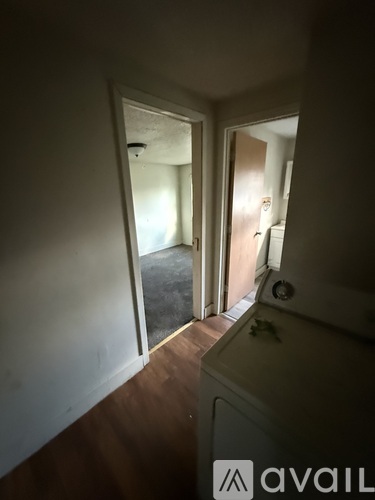 A hallway with a door on the left and a bathroom on the right.
